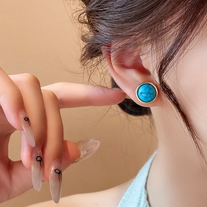 Vintage round turquoise stud earring with gold plating shown on model ear lobe