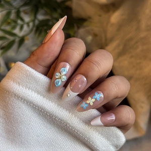 Handmade almond press-on nails in nude with 3D floral designs and French tips
