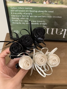 Détail de pinces banane fleur rose en satin noir et crème avec nœuds élégants