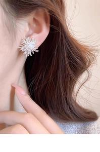 Close-up of elegant silver firework stud earrings with sparkling cubic zirconia on model