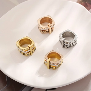 Detailed shot of four roman numeral rings in gold silver and rose gold on ceramic tray