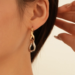 Close-up of model wearing two-tone gold and silver twisted teardrop earrings
