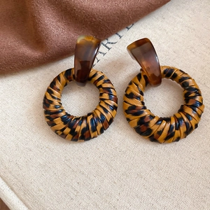 Close-up of geometric leopard print resin earrings with leather texture and silver pins