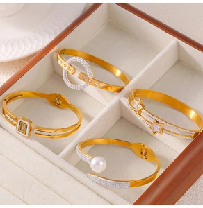 Detailed view of four gold-plated hollow bangles with zircon and pearl accents on velvet