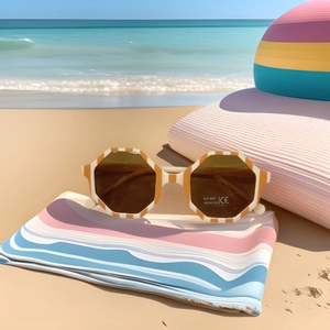 Kids orange striped octagonal sunglasses with UV400 protection on a summer beach background