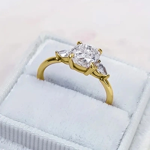 Macro-opname van driestenen ring met kussenslijpsel en gouden band in fluwelen doosje