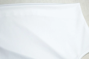 Détail du tissu blanc élastique montrant une texture lisse et des coutures de qualité