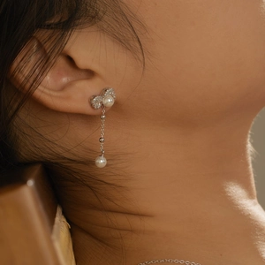 Elegant drop earrings featuring a silver bow, sparkling stones, and freshwater pearls