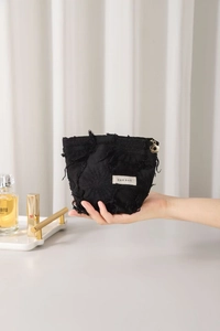 Close-up of black fringe linen cosmetic bag with a gold flower zipper pull