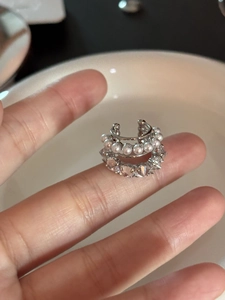 Vue macro d'un earcuff argenté à trois couches avec perles et pierres de zircone éclatantes