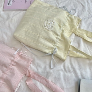 Borse tote in tela con coulisse, pizzo a cuore e nastri su sfondo di tessuto bianco