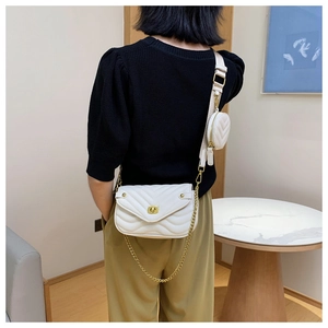 Detail of white quilted leather bag showing metal chain and round coin purse attachment