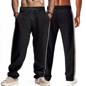 Detail of black corduroy sweatpants featuring white side stripes and drawstring waistband