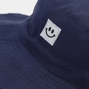 Detail of navy blue kids bucket hat featuring a smiley face patch and reinforced stitching