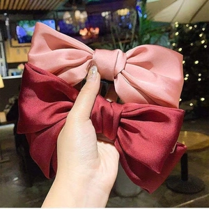 Détails de grands nœuds à cheveux en satin rose et bordeaux avec une finition lisse