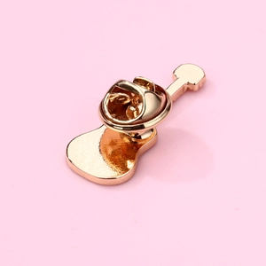 Detail view of a gold guitar-shaped enamel brooch with a metal butterfly clutch back