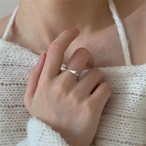 Macro view of minimalist 925 sterling silver bow ring worn with white sweater