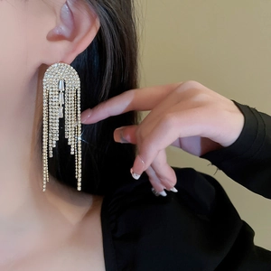 Close-up of golden tassel earrings with sparkling rhinestones worn by a model