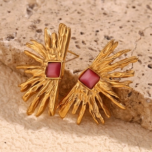 Detailed macro of 18K gold starburst earrings with inlaid fuchsia square gemstone