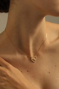 Irregular gold heart pendant necklace with zircon inlays on model's neck