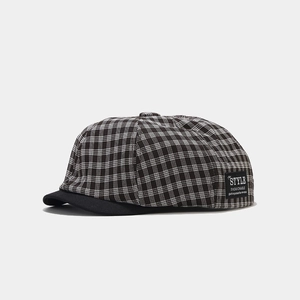 Close-up of black and white checkered newsboy cap with side logo and short brim detail