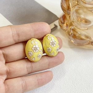 Detail of vintage oval enamel flower earrings with sparkling rhinestones in hand