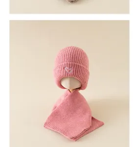 Close-up of pink knit baby beanie and scarf set with delicate heart embroidery details