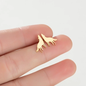 Cute wolf silhouette stud earrings in gold finish held by hand on white background