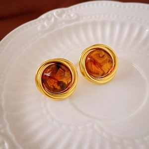Macro detail of French vintage resin stud earrings with amber marble and gold metal frame