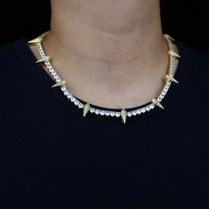 Close-up of hip hop tennis chain with iced out gold spike pendants on model