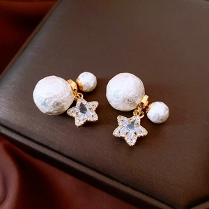Macro shot of double-pearl star earrings with gold plating and sparkling zircon stones