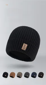 Close-up showing the soft ribbed knit texture and leather logo detail of the winter beanie
