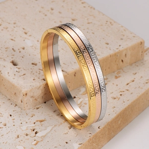 Classic maze pattern bangle set in gold silver and rose gold on a stone base