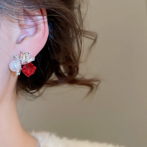 Close-up of geometric silver earring with red crystal, white pearl and square diamonds