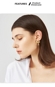 Detailed view of model wearing gold bow-shaped earrings with a polished mirror finish