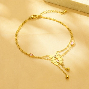 Detail of gold double-layer butterfly bracelet with pink stones on warm silk background