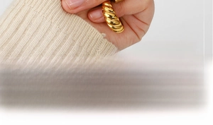 Detailed view of an 18K gold croissant ring with spiral texture worn on finger