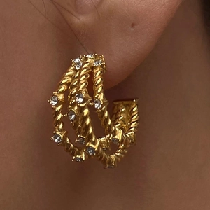 Close-up of 18k gold plated C-shaped triple twist hoop earrings with crystals on ear