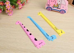 Detailed view of colorful giraffe plastic rulers in pink blue and yellow on a wooden desk