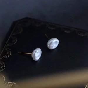 Detailed view of white baroque pearl earrings on a vintage black jewelry box