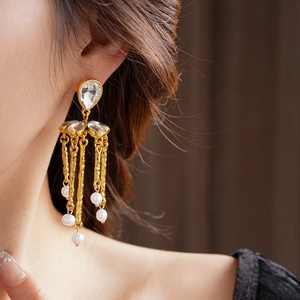 Close-up of vintage gold tassel earrings featuring water-drop crystals and white pearls