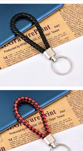 Dettaglio di portachiavi in pelle intrecciata nera e rossa con anelli metallici