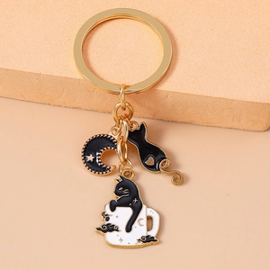 Detail of golden metal keychain featuring black enamel moon and cute cat charms