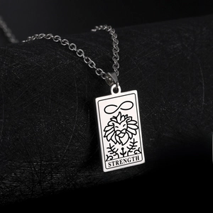 Macro view of stainless steel Strength Tarot necklace featuring lion and infinity symbols