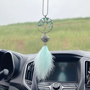 Macro view of a Life Tree car hanging ornament with green stones and light blue feathers