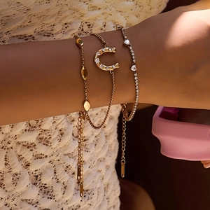 Detailed view of three-piece gold-tone bracelet set with horseshoe and leaf charms