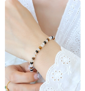 Détail du bracelet en perles avec jade blanc agate noire et oeil de tigre au poignet