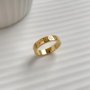 Macro shot of gold star ring featuring a central sparkling zircon and engraved stars