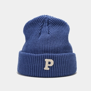 Macro shot of dark blue knitted beanie featuring a white embroidered letter P on cuff