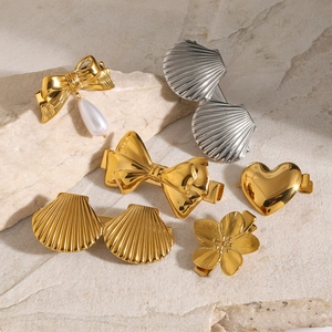 Collection of 18k gold and silver bow, heart and shell hair clips on a stone surface